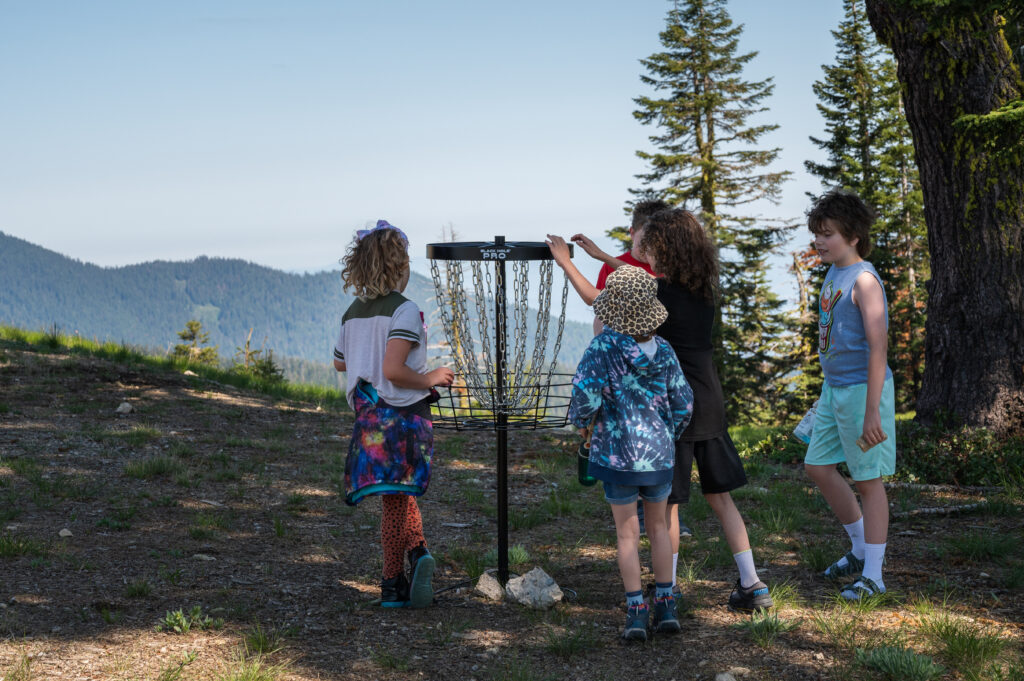 Kids inspecting a disc golf basket on Mt. Ashland